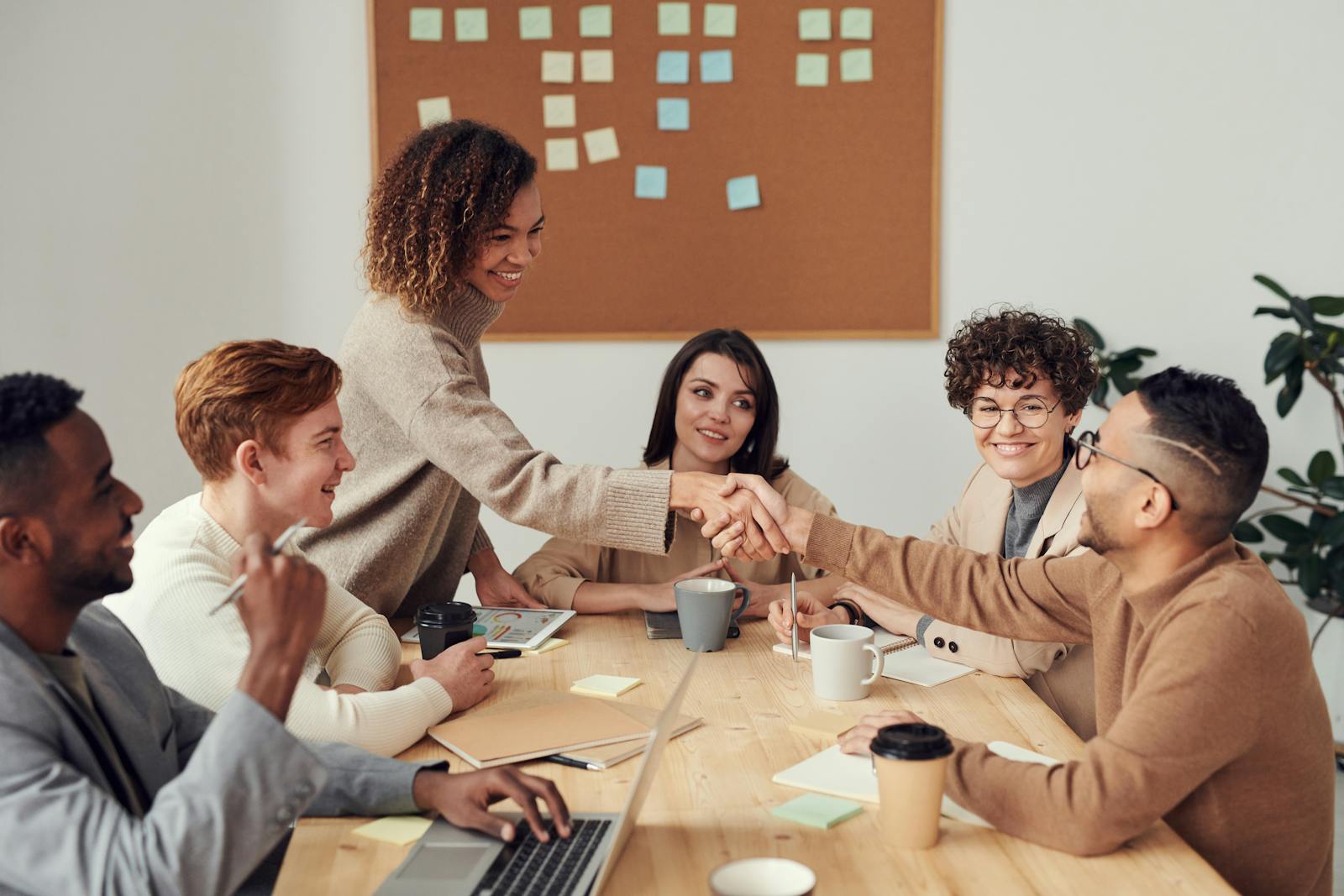 Equipo profesional celebrando un logro alrededor de una mesa de trabajo